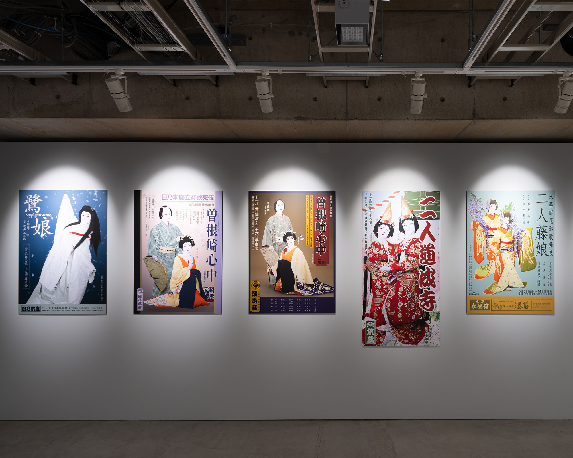 Film posters related to “KOKUHO” displayed in a row along the gallery wall, presenting different visuals within a concrete exhibition space.